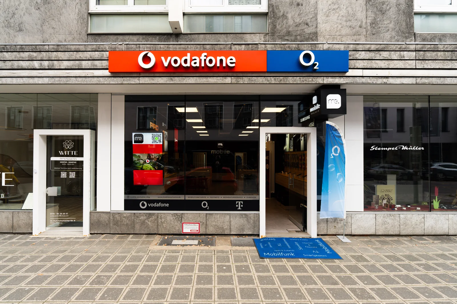 Ladenfront von Mobile Exclusive in der Dr.-Kurt-Schumacher-Straße 8 in Nürnberg, Vodafone- und O2-Schild über dem Schaufenster, Eingangstür offen