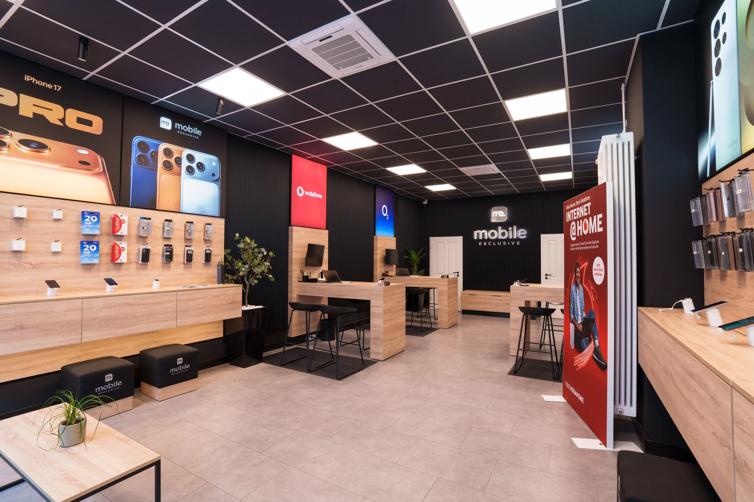 Verkaufsraum von Mobile Exclusive in Nürnberg: links die Gerätewand, in der Mitte zwei Beratungstische mit Barhockern, dahinter die Anbieterflächen von Vodafone und O2